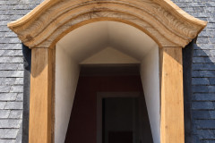 Lucarne en bois sculpté sur toit d’ardoise